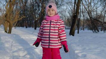 Smiling child kid walking, having fun, relaxing, looking around on snowy road in winter park forest video
