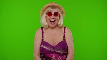 Amazed senior pensioner woman tourist in swimsuit shocked by sudden victory saying wow on chroma key video