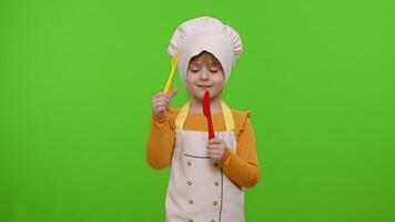 Child girl dressed chef cook with fork and knife, waving head approval on chroma key background video