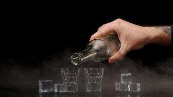 Two hands with glasses of vodka making cheers, raising toast on black background with ice cubes video