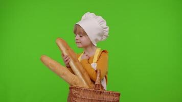 Child girl kid dressed as professional cook chef smiling and showing basket with baguette and bread video