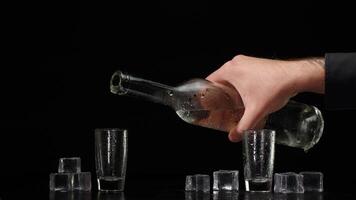 Two hands with glasses of vodka making cheers, raising toast on black background with ice cubes video