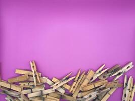 Old wooden clothespins centered at the bottom of the image on a purple background top view photo