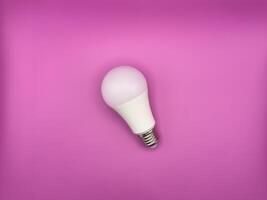White diode light bulb on purple background without unnecessary objects top view photo