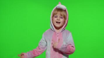 Little blonde child girl smiling, dancing, celebrating in unicorn pajamas costume on chroma key video
