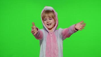 Little child girl smiling, waving greeting, hello or bye with hand in unicorn pajamas on chroma key video