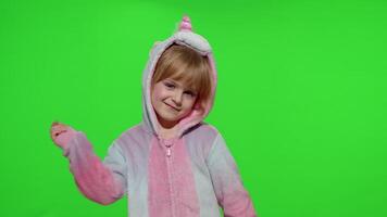Little blonde child girl smiling, dancing, celebrating in unicorn pajamas costume on chroma key video