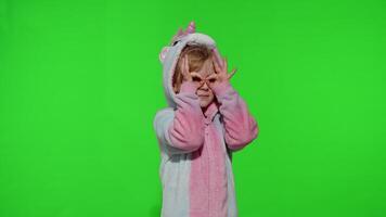 Child girl in unicorn pajamas fooling around, looks through her hands as if through binoculars video