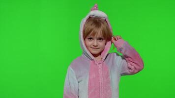 Child girl in unicorn pajamas making silly funny faces, fooling around, showing tongue on chroma key video