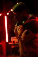 Emotional moment captured at night in a vibrant urban setting with red lights and a contemplative figure photo
