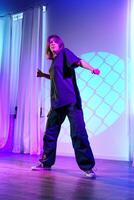 Dynamic dance performance by a female artist on stage during a colorful light show in an urban setting photo
