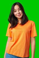 Young woman poses confidently in an orange t-shirt against a vibrant green background photo