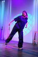Dancer performs expressive routine in dimly lit studio with colorful lighting during evening session photo