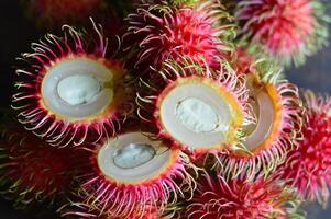 Macro shot of fresh rambutan showing vivid red skin and hairy texture. Perfect for exotic fruit themes, tropical food visuals, or natural product presentations. photo