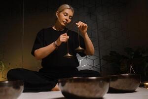 Practicing mindfulness and meditation with singing bowls in a serene indoor setting during the evening photo