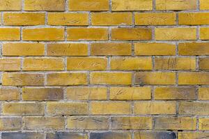 A brick wall with a yellow color. The bricks are arranged in a pattern. photo