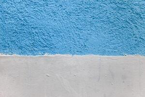 A wall with a blue and white stripe. The blue stripe is painted on top of the white. photo