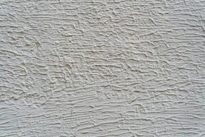 A wall with a white paint that has a texture. The texture is made up of lines and swirls. photo