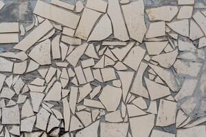 A wall with many pieces of broken tiles. The wall is white. The tiles are broken in different shapes and sizes. photo