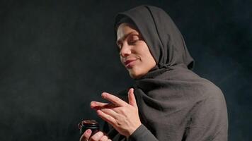 woman wearing hijab appears be applying skincare product. She has focused and confident expression while engaging in her self care routine in indoor setting video