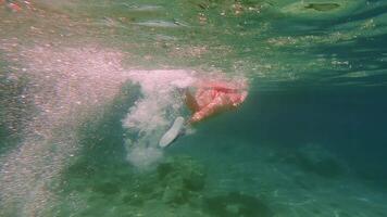 Swimmer wearing red diving fins gliding gracefully through pristine turquoise waters, exploring rocky underwater seascape with sunlight filtering through crystal clear environment video