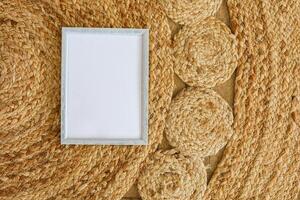 Decorative woven placemat with blank frame on a rustic table surface photo