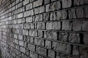 Black brick wall texture with sharp edges and varying shadows creating depth photo