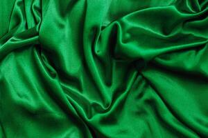 Rich green satin fabric draped elegantly with soft folds and texture details photo