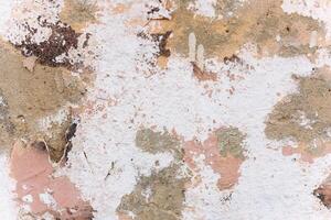 Unique textured wall with peeling paint exhibiting natural color variations and patterns photo