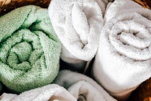 Freshly rolled green and white towels inside a woven basket at a spa or home setting photo