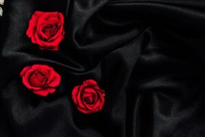 Soft black fabric with vibrant red roses arranged artistically for a romantic atmosphere photo