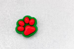 Bright red paw print shaped toy sits on a light gray surface photo