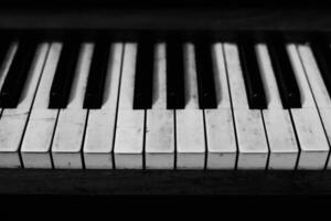 Close up of piano keys showing wear and tear in a black and white setting photo