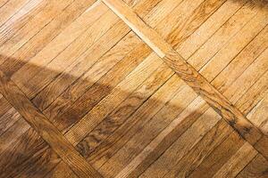 Wooden floor with diagonal patterns and soft sunlit shadows creating a warm ambiance photo