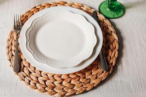 Elegant dining setup featuring a white plate on a woven placemat with silverware photo