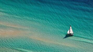 Aerial View of a Lone Sailboat on a Turquoise Ocean photo