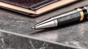 Closeup of Grey Metallic Pen and Brown Notebook on Dark Grey Marble Surface photo