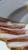 Sliced pork pastrami with a French baguette. The sausage is on a retro-style cooking tray and on food paper. Slow motion filming on the slider. We also use fresh lettuce leaves video