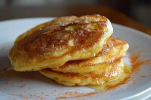 Stack of pancakes with honey or maple syrup and cinnamon on white plate photo