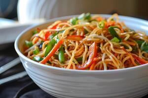 Chow mein noodles with colorful vegetables in white bowl being served photo