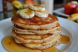 Stack of pancakes with sliced banana and syrup drizzled on top photo