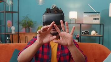 Man using virtual reality futuristic technology headset to play simulation 3D game at home video