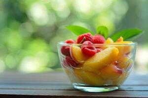 Glass bowl overflowing with fresh peaches and raspberries on wooden table photo
