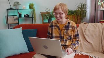 Woman sitting on home couch, looking at camera, making conference call with friends or family video