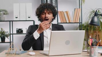Inefficient tired lazy business man working sleeping on laptop computer with eyes stickers on face video