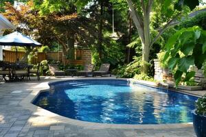 Backyard inground swimming pool with waterfall cascading into crystal clear water on sunny summer day photo