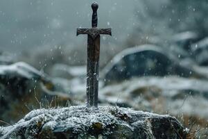 Medieval sword stuck in stone covered with snow during snowfall photo