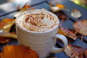 Pumpkin spice latte with whipped cream and autumn leaves creating cozy atmosphere photo