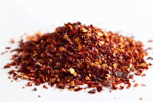 Pile of dried chili flakes forming small mountain on white background photo
