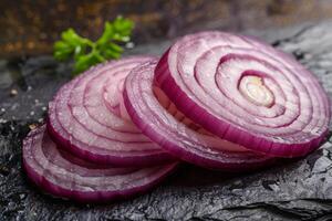 Sliced red onion on slate with parsley and pepper photo